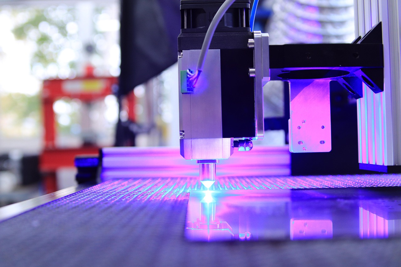Ein Lasergerät mit blauem Licht bearbeitet eine reflektierende Oberfläche in einer industriellen Umgebung.